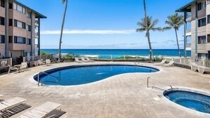 Ein Poolbereich mit Liegestühlen, Palmen und Blick auf das Meer.