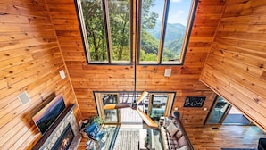 A spacious cabin with a large central fireplace, a ceiling fan, and a cozy seating area.