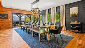 A dining area with a long wooden table, benches, and hanging pendant lights.