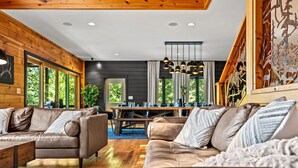 A modern living room with leather sofas, a wooden dining table, and large windows.