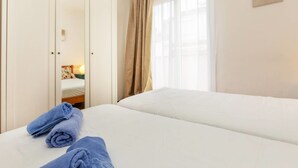 Une chambre d’hôtel avec un lit, une armoire et une fenêtre avec des rideaux.
