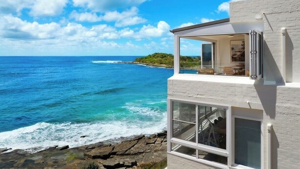 Un bâtiment moderne doté de grandes fenêtres offrant une vue sur la côte.
