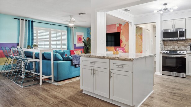 A modern kitchen with white cabinets, stainless steel appliances, and a wooden floor. - Pickleball, Basketball, Heated Pool, Mini Golf! (Seminole)