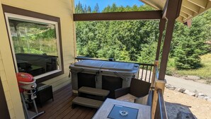 Una terraza techada al aire libre con una parrilla, un jacuzzi y una mesa con sillas.