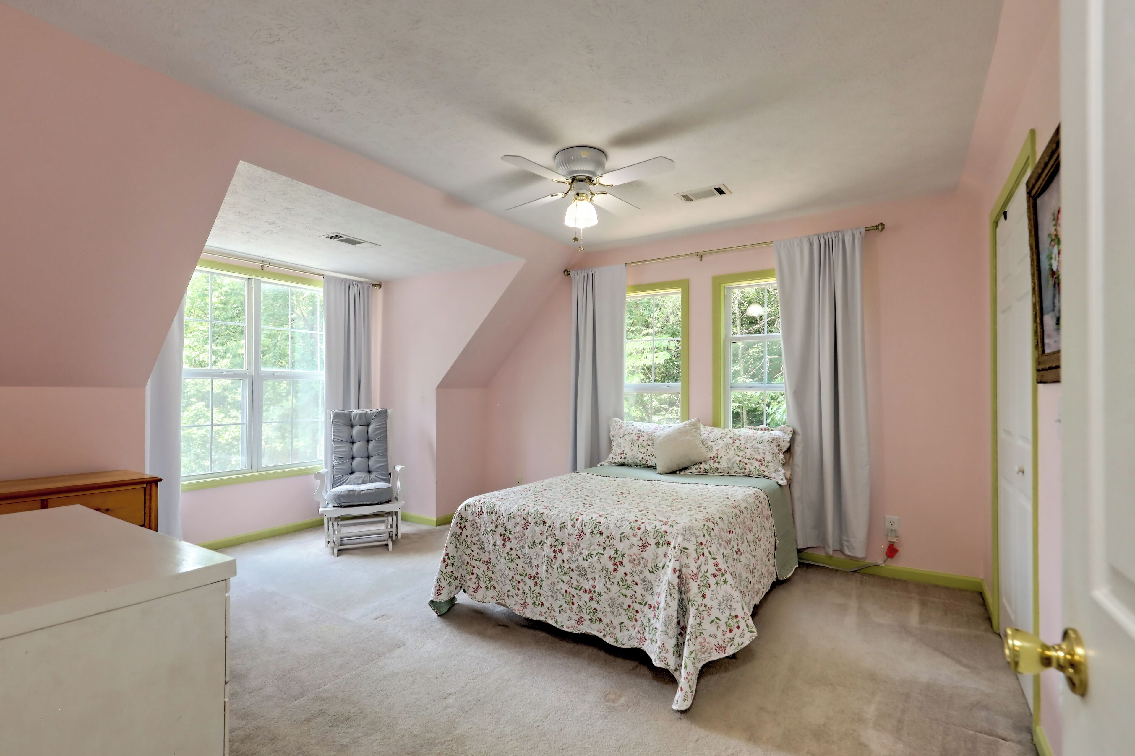 A bedroom with a bed, a chair, a desk, and a ceiling fan.