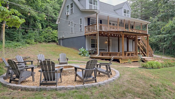 Een tweelaags huis met een houten terras en een rond zitgedeelte met Adirondack-stoelen.