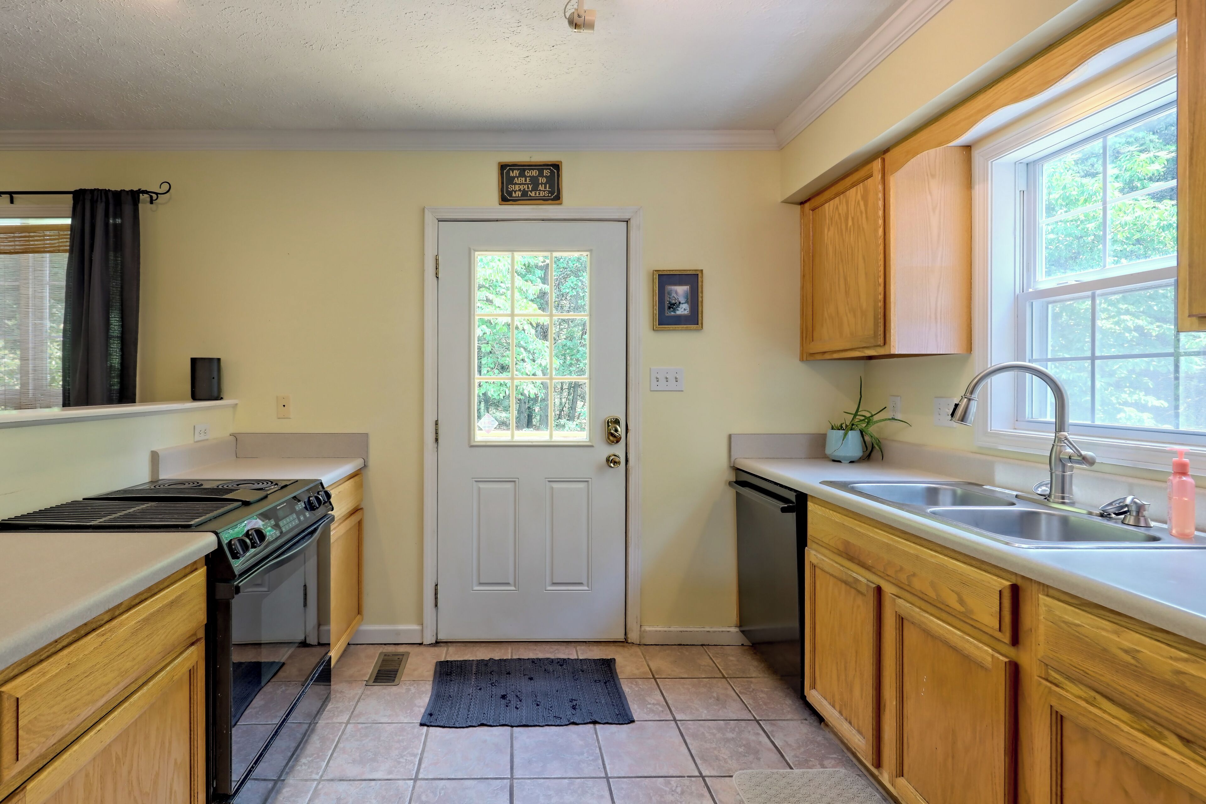 A kitchen with wooden cabinets, a stove, a sink, and a window.