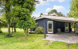 A single-story house with a dark exterior, a covered porch, and a clear glass door. - Beach front home in Nykøbing Sj with WiFi (Nykøbing Sj)