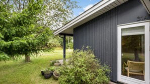 A dark-colored building with a glass door and a number '31A' above it. There are potted plants and a wooden chair outside. - Beach front home in Nykøbing Sj with WiFi (Nykøbing Sj)