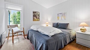 A bedroom with a bed, two bedside tables, a chair, and a window with a view of greenery. - Beach front home in Nykøbing Sj with WiFi (Nykøbing Sj)