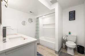 Et moderne badeværelse med vask, spejl og toilet.