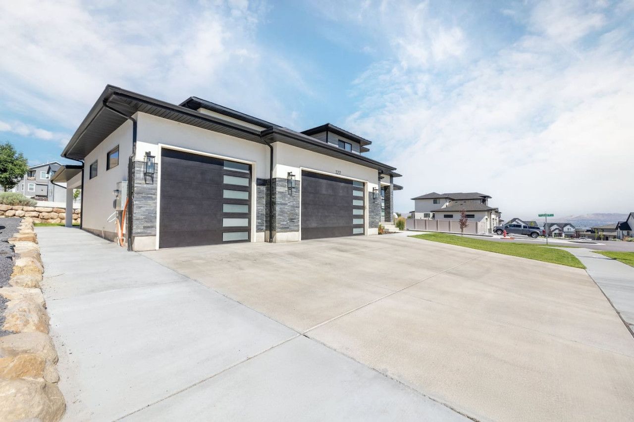 A modern two-story house with a garage, a driveway, and a clear sky.