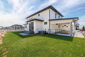Une maison moderne à deux étages, dotée d’un patio couvert, d’une pelouse bien entretenue et d’un système de climatisation.
