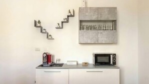 A kitchenette with a microwave, coffee maker, and a cabinet with shelves. - [ La Vie en Rose ] Between Tranquility and Movida (Sant'Angelo)