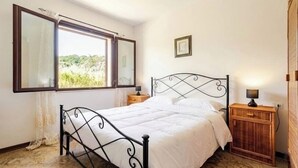 A bedroom with a bed, a nightstand, a window with curtains, and a wall-mounted picture. - [ La Vie en Rose ] Between Tranquility and Movida (Sant'Angelo)
