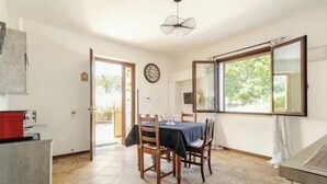 A dining area with a table and chairs, a clock on the wall, and a window with a view of greenery. - [ La Vie en Rose ] Between Tranquility and Movida (Sant'Angelo)