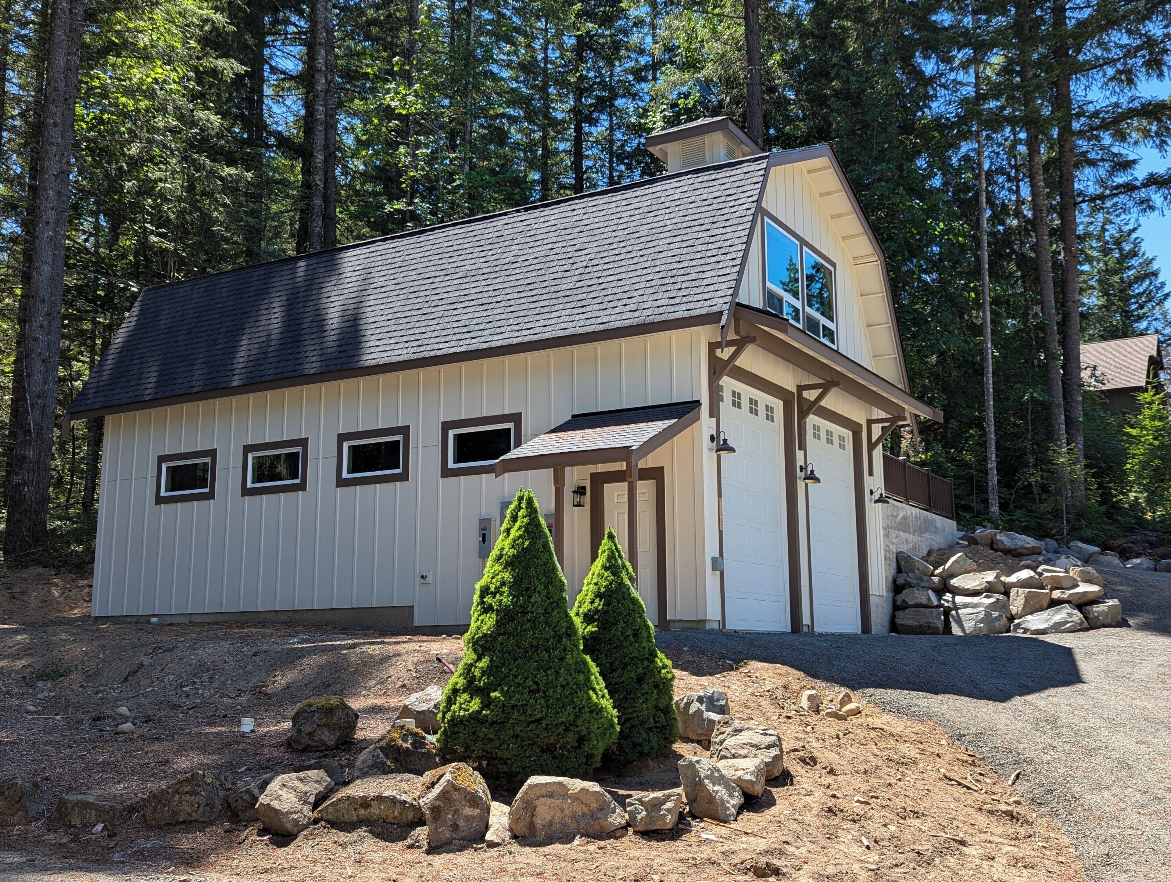A small, single-story cabin with a sloped roof, a front porch, and a garage.