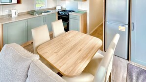 A compact kitchen with a dining area, including a table, chairs, a microwave, a stove, and a refrigerator.