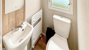 A bathroom with a white sink, toilet, and a window with a view.