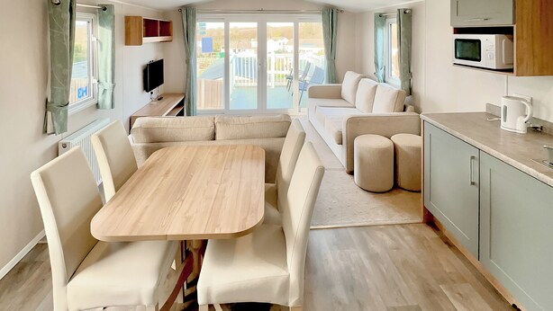 A modern kitchen with a dining area, a TV, and a view of the outside.