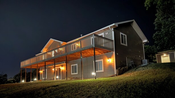 Een modern huis met een balkon, meerdere ramen en een goed verlichte gevel in de avond.