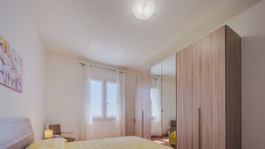 Ein Schlafzimmer mit Bett, Kleiderschrank, Fenster und einem Bild an der Wand.