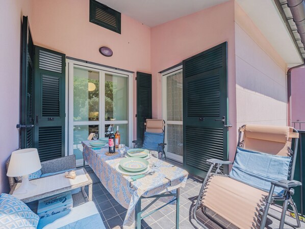 Un petit espace patio avec une table dressée pour deux personnes, une chaise et un canapé.