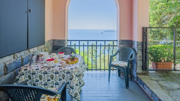 Un balcon avec une table dressée pour le dîner, offrant une vue panoramique sur la mer.