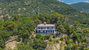 Une maison dotée d’un balcon, entourée d’arbres et de collines.