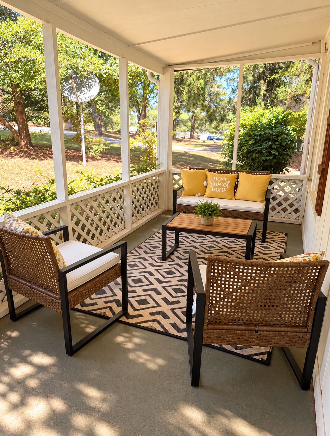 A covered porch with wicker furniture, a patterned rug, and a view of the outdoors.