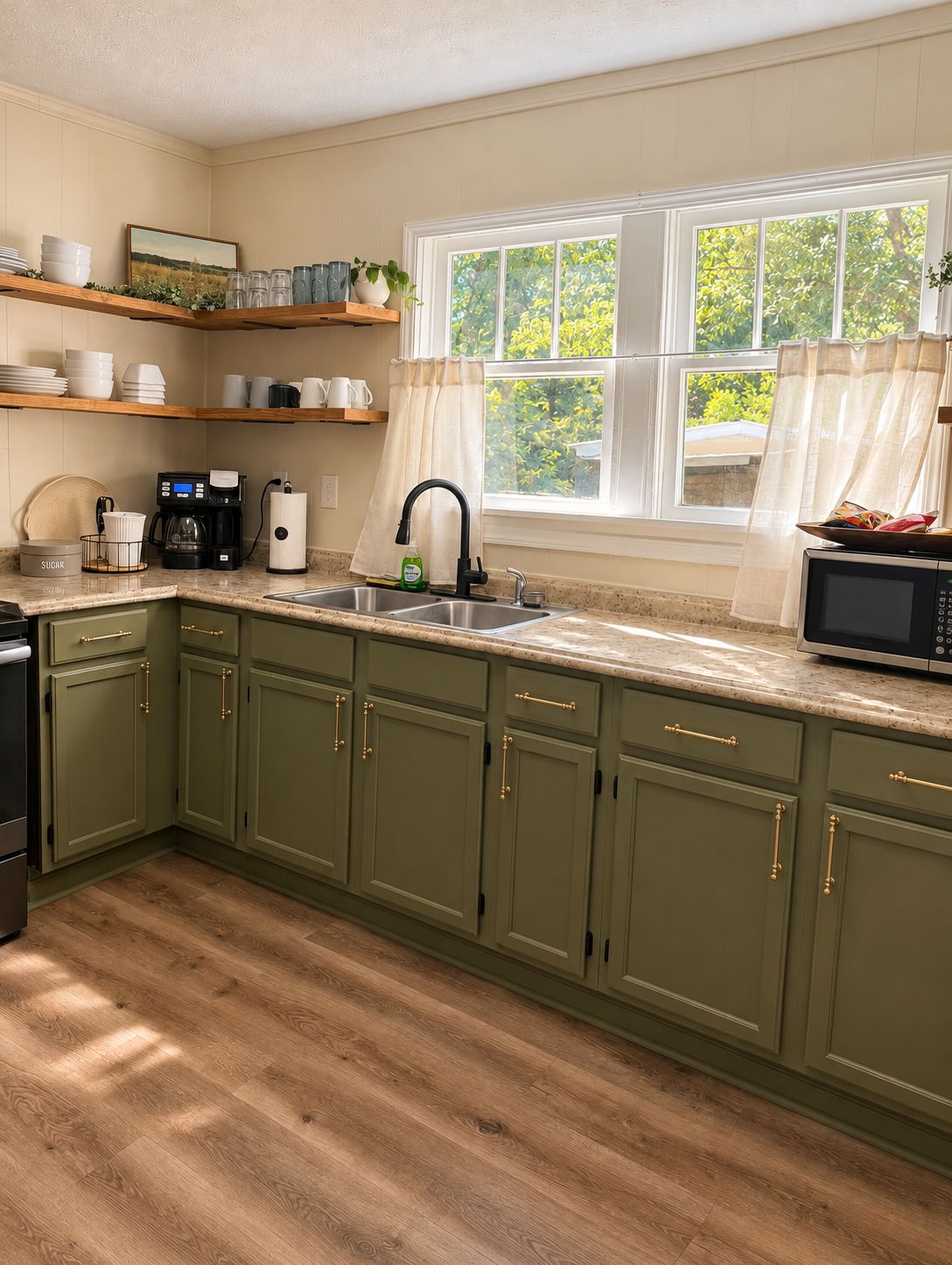 A kitchen with green cabinets, a stainless steel sink, a coffee maker, and a microwave.