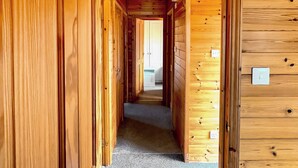 A wooden hallway with doors leading to rooms, carpeted floor, and a visible light switch on the wall. - 3 bedroom accommodation in Hayle (Hayle)