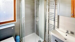 A bathroom with a glass shower enclosure, a toilet, a sink, and a towel rack. - 3 bedroom accommodation in Hayle (Hayle)