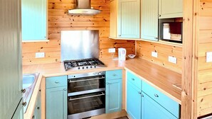 A compact kitchen with a gas stove, oven, and a microwave. - 3 bedroom accommodation in Hayle (Hayle)