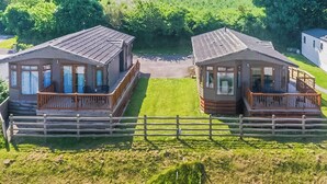 Two cabins with wooden decks and a wooden fence in front. - 3 bedroom accommodation in Hayle (Hayle)