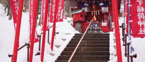 Una escalera conduce a un edificio rojo con escalones cubiertos de nieve y pilares rojos.