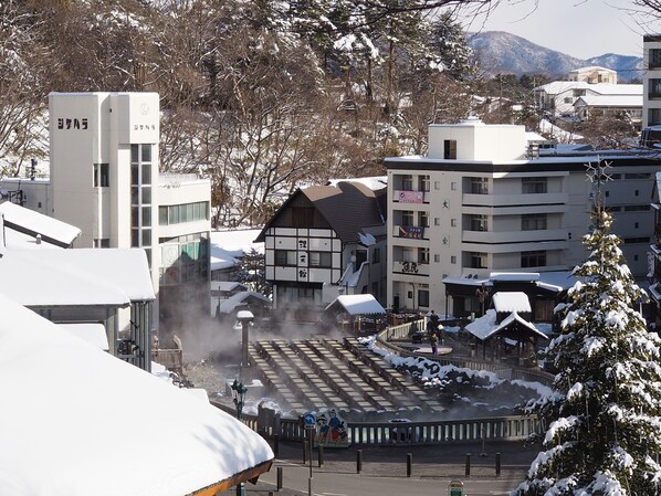 A traditional Japanese building with a snow-covered roof, surrounded by modern buildings and a snowy landscape.