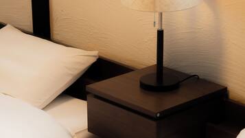A neatly made bed with white linens and a small bedside table with a lamp.