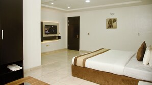 A hotel room with a bed, a television, a painting, and a wardrobe. - 1Bed - Balcony - Pool - Gym - Spa (Lagos)