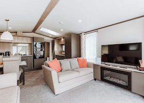 A modern RV interior with a living area, kitchenette, and a TV.