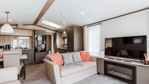A modern RV interior with a living area, kitchenette, and a TV.