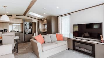 A modern RV interior with a living area, kitchenette, and a TV.