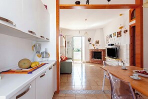 A kitchen with a blender, fruits, and a dining area with a table and chairs.
