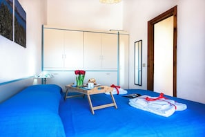 Un dormitorio con una cama, una mesita de noche de madera con una bandeja, una lámpara y un espejo.