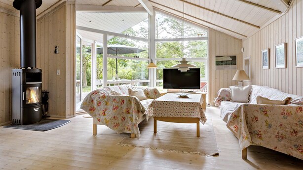 A cozy room with a fireplace, wooden furniture, and large windows offering a view of the outdoors. - 2 bedroom gorgeous home in Slagelse (Slagelse)
