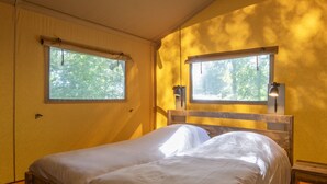 Un dormitorio con dos camas, cabeceros de madera y dos ventanas con cortinas.