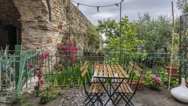 Um edifício rústico de pedra com um banco e uma mesa de madeira num jardim.