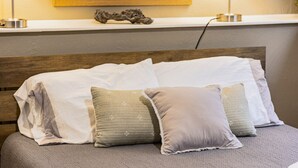 A bed with white and grey bedding, a wooden headboard, and a small decorative piece on the wall above. - 1 bed 1 bath | Quiet neighborhood (Sioux Falls)