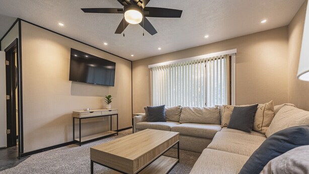 A modern living room with a sofa, coffee table, and a TV mounted on the wall.