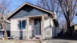 A single-story house with a stone foundation, a dark shingled roof, and a front door marked with the number 20. - Stylish, comfort-first 2BR/1BA (Sioux Falls)